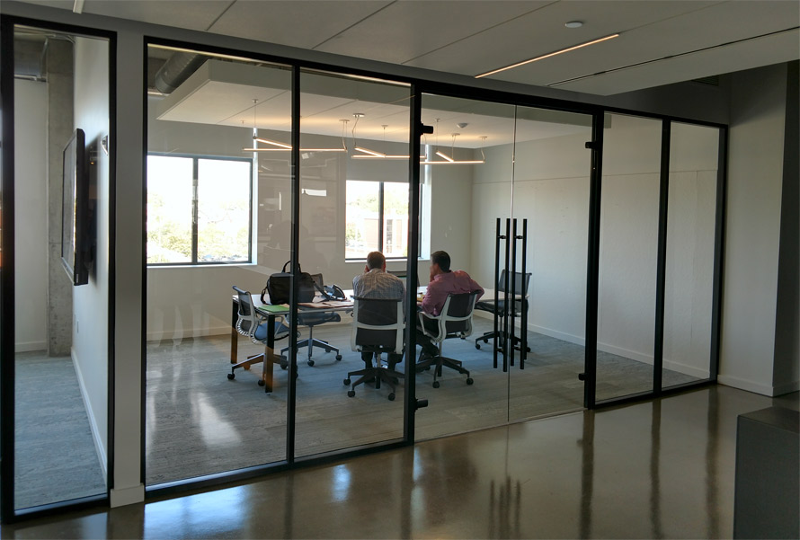 Floor-to-ceiling glass conference room walls with black aluminum framing