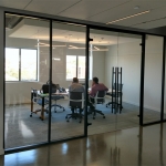 Floor-to-ceiling glass conference room walls with black aluminum framing