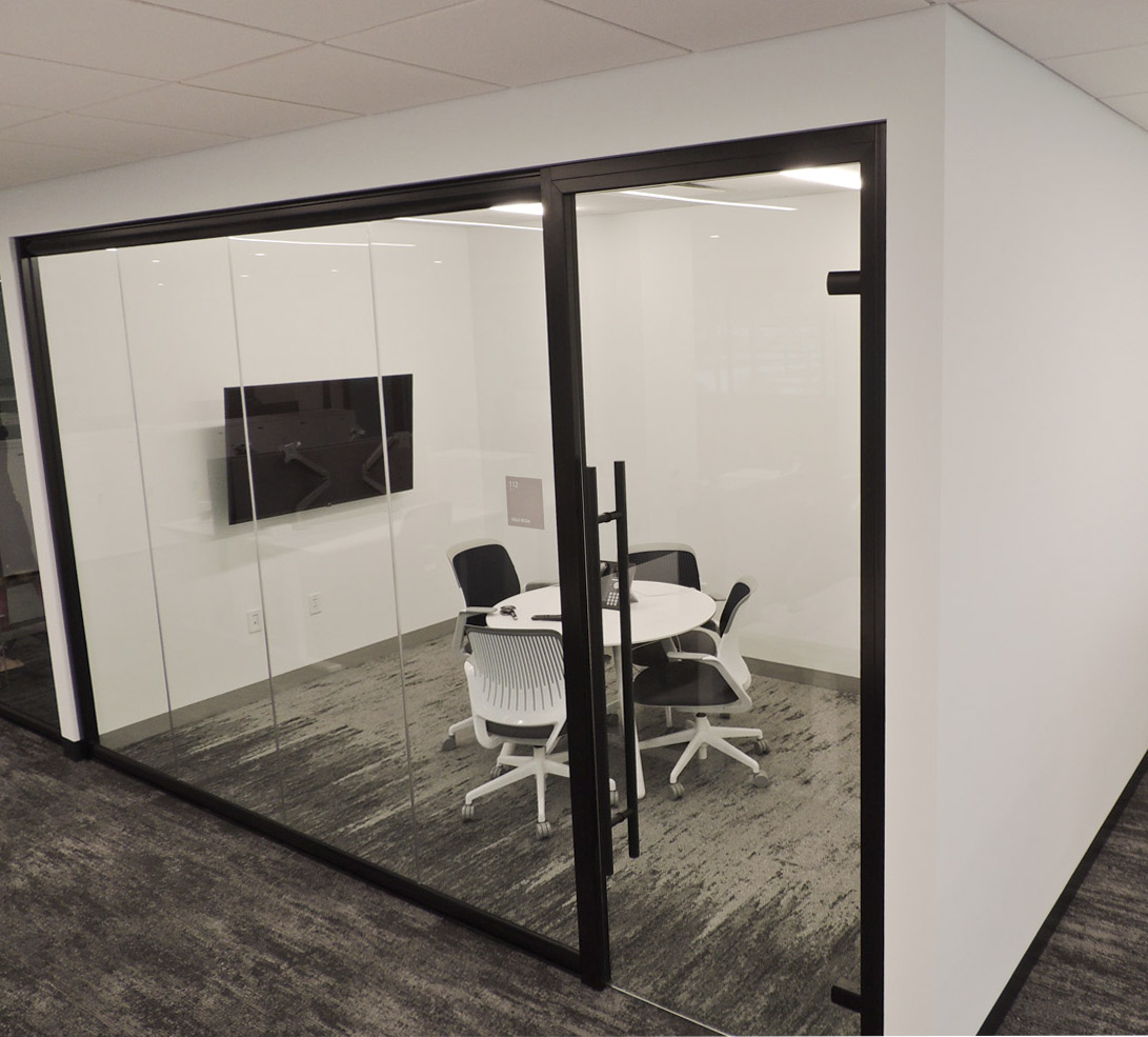 Floor-to-ceiling glass huddle room with black frame finish and frameless glass swing door #1649